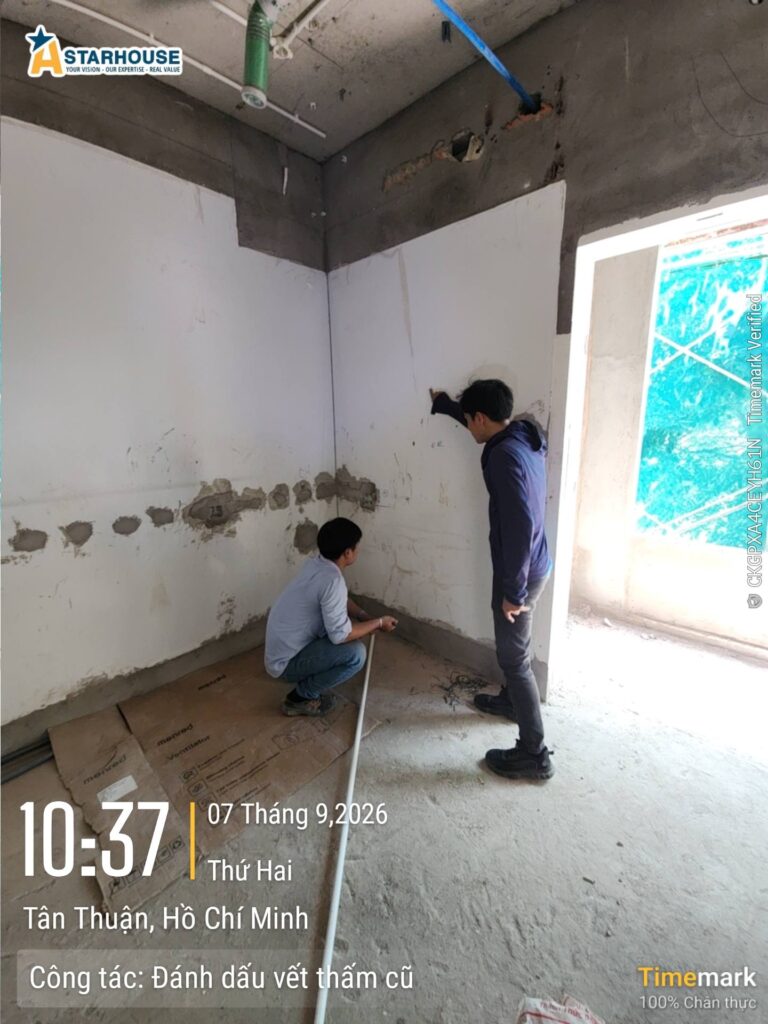 Kỹ sư đánh dấu vết thấm cũ trên chân tường — đã đánh dấu thì phải xử lý, không tô đè